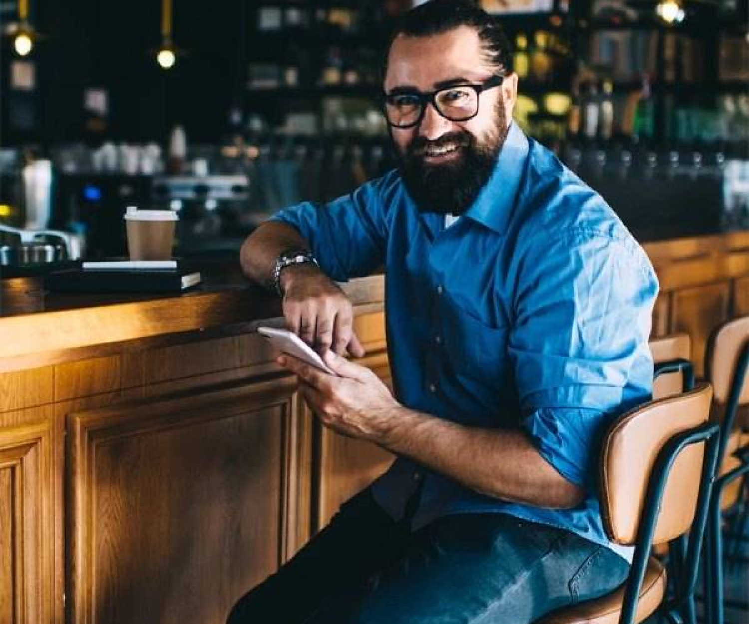Business owner at a bar counter using a phone to manage music