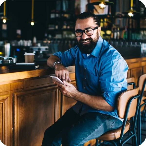 Business owner at a bar counter using a phone to manage music